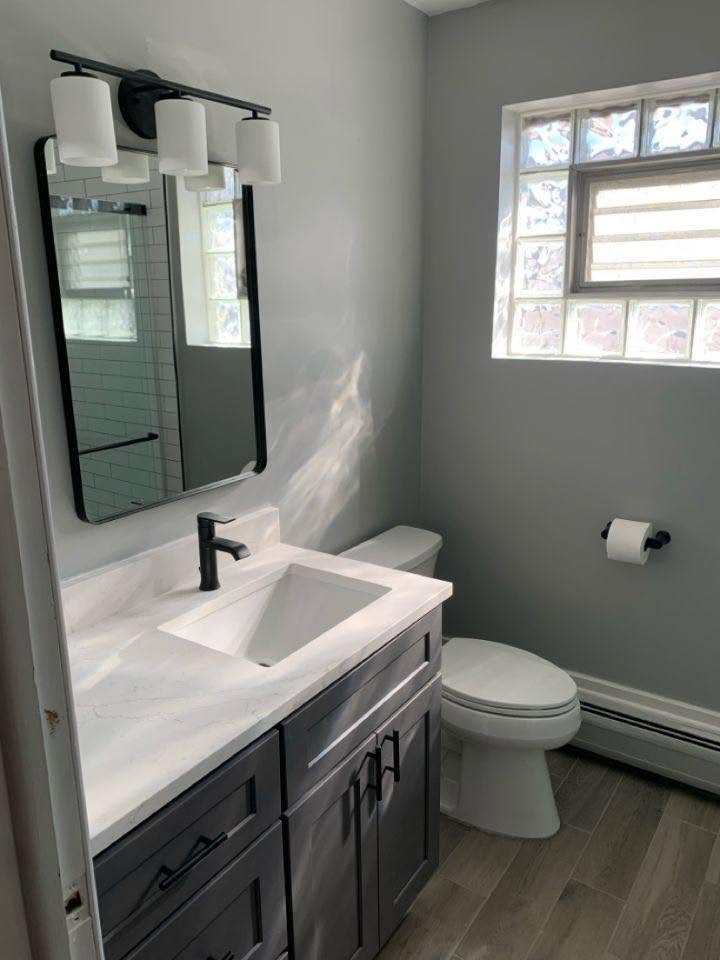 Modern bathroom with grey shaker vanity, quartz top and black fixtures