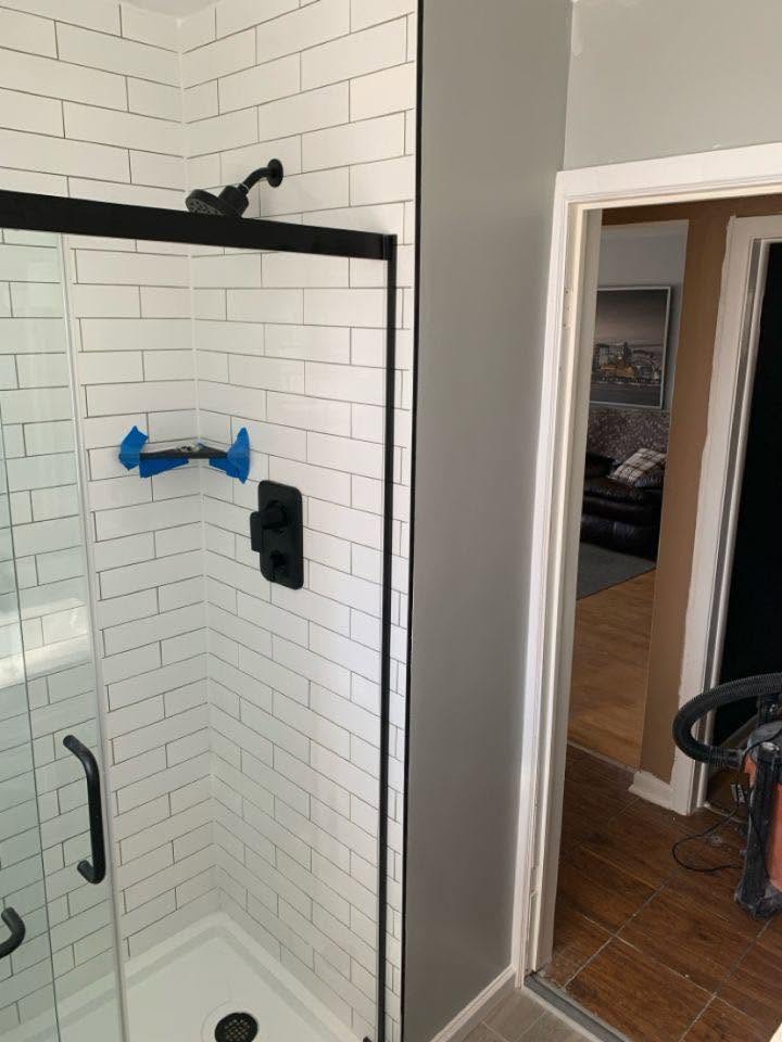White subway tile shower with black trim and sliding glass door