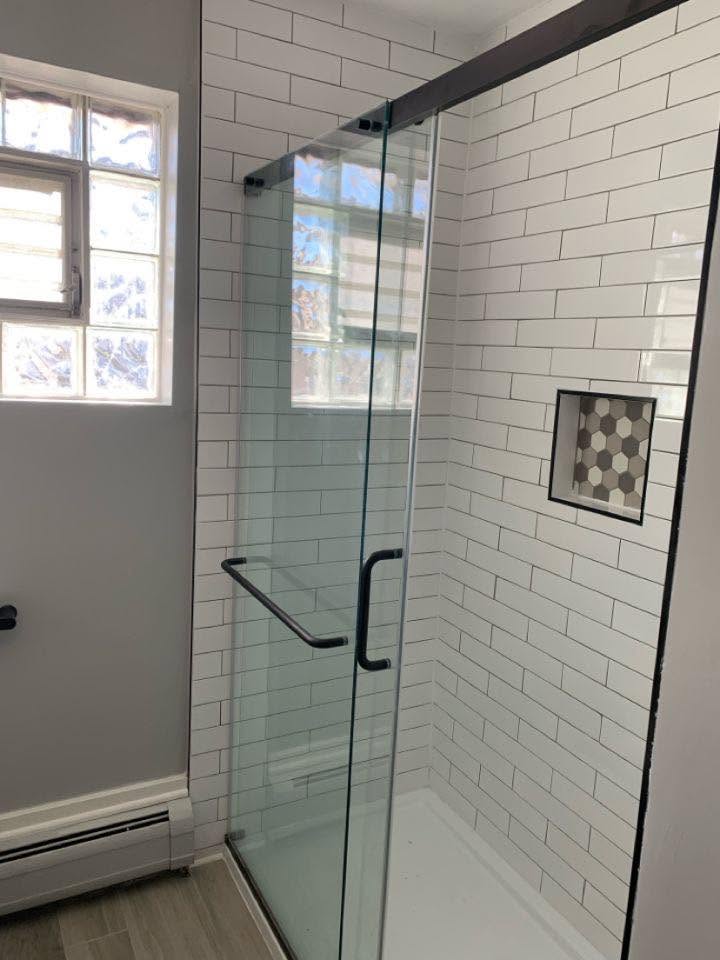 New tiled shower with glass sliding door and tiled niche