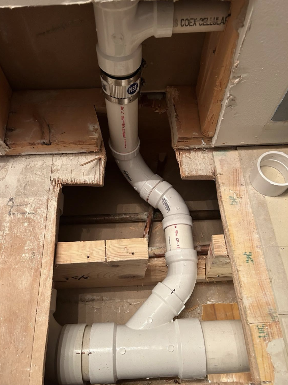 New PVC drain rerouted through open bathroom floor framing