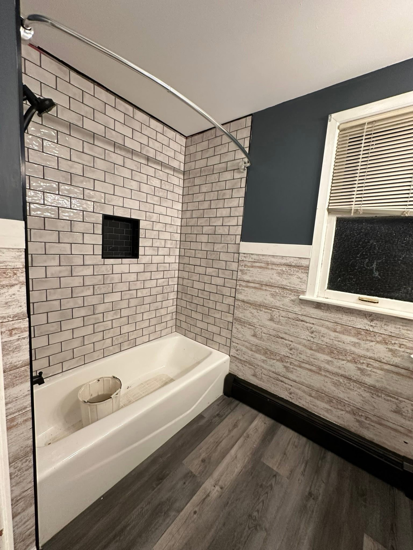 Subway tile tub surround with black niche and new luxury vinyl plank flooring