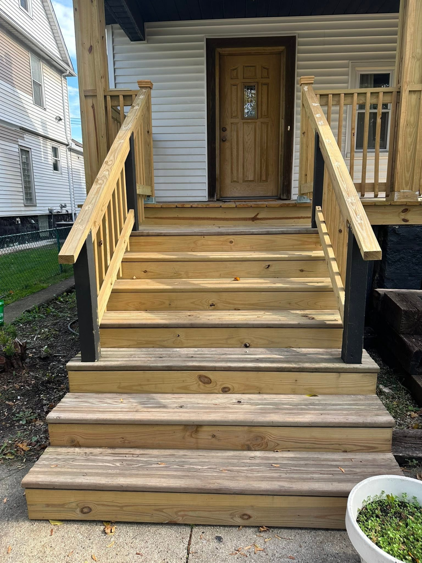 Rebuilt front porch steps and railings at a wood entry door