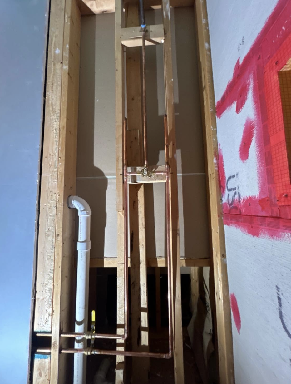 New copper shower supply lines installed in an open bathroom wall
