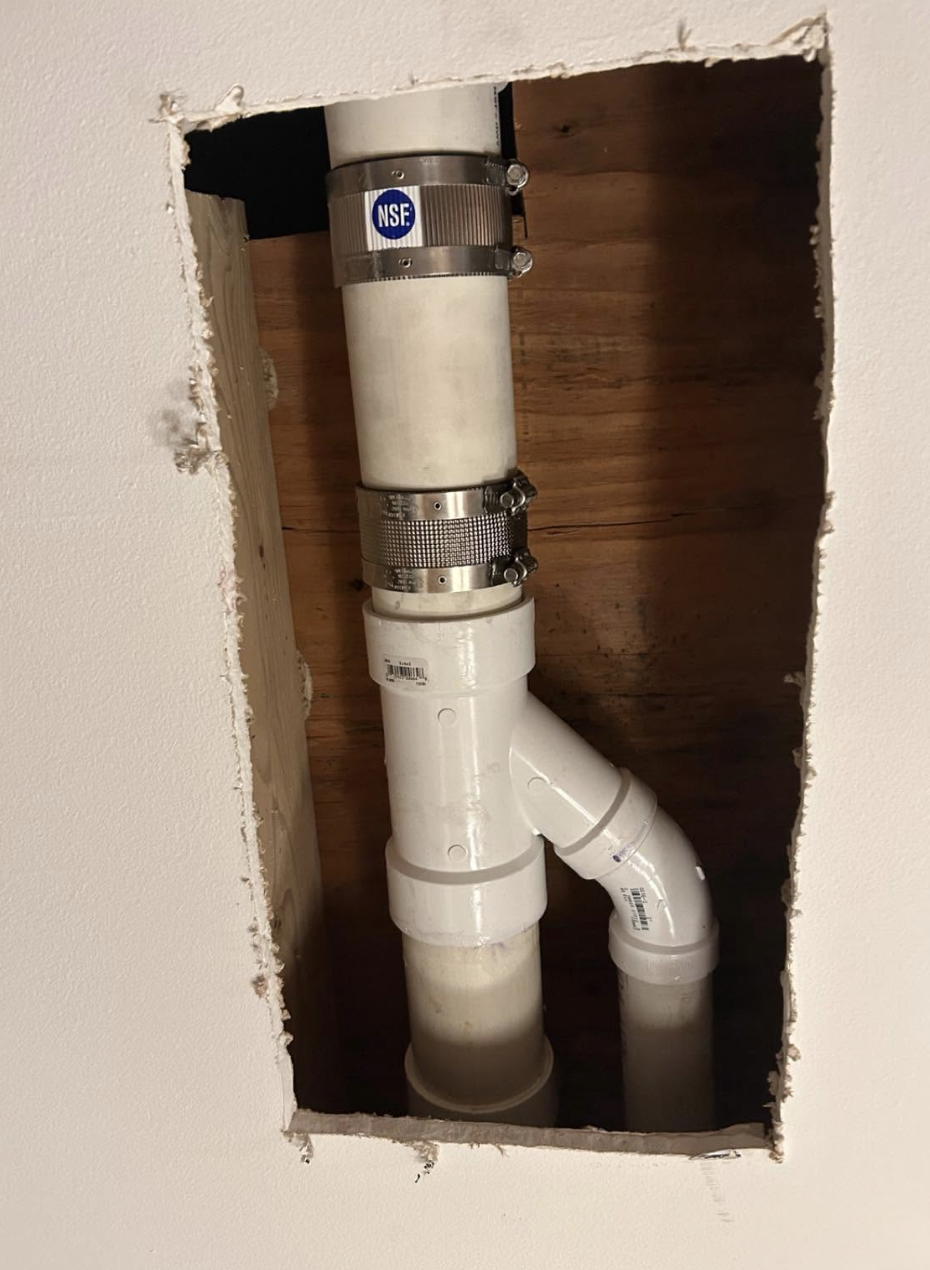 New vertical PVC drain connection installed behind drywall