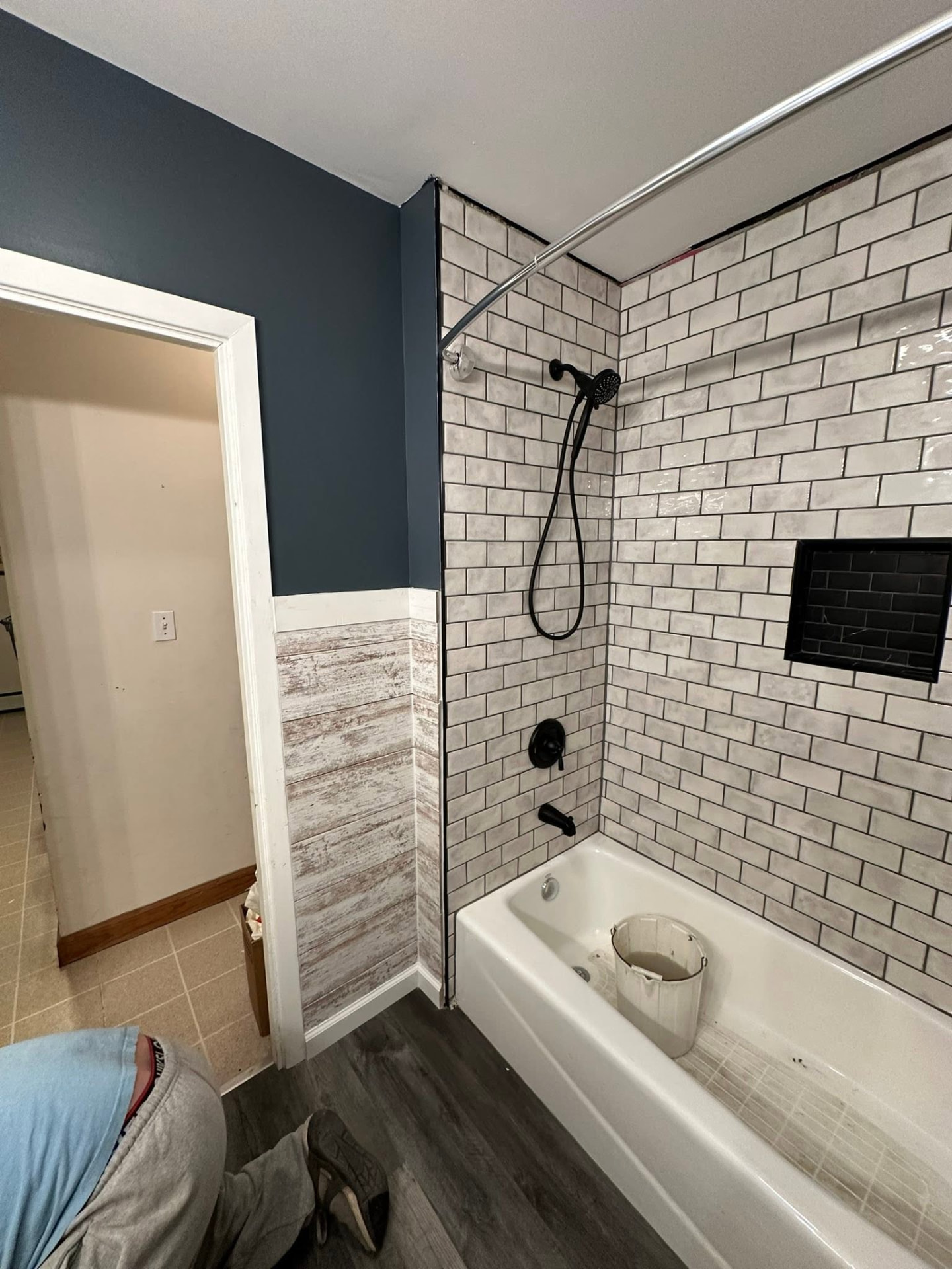 Subway tile tub surround with black fixtures and shiplap accent wall