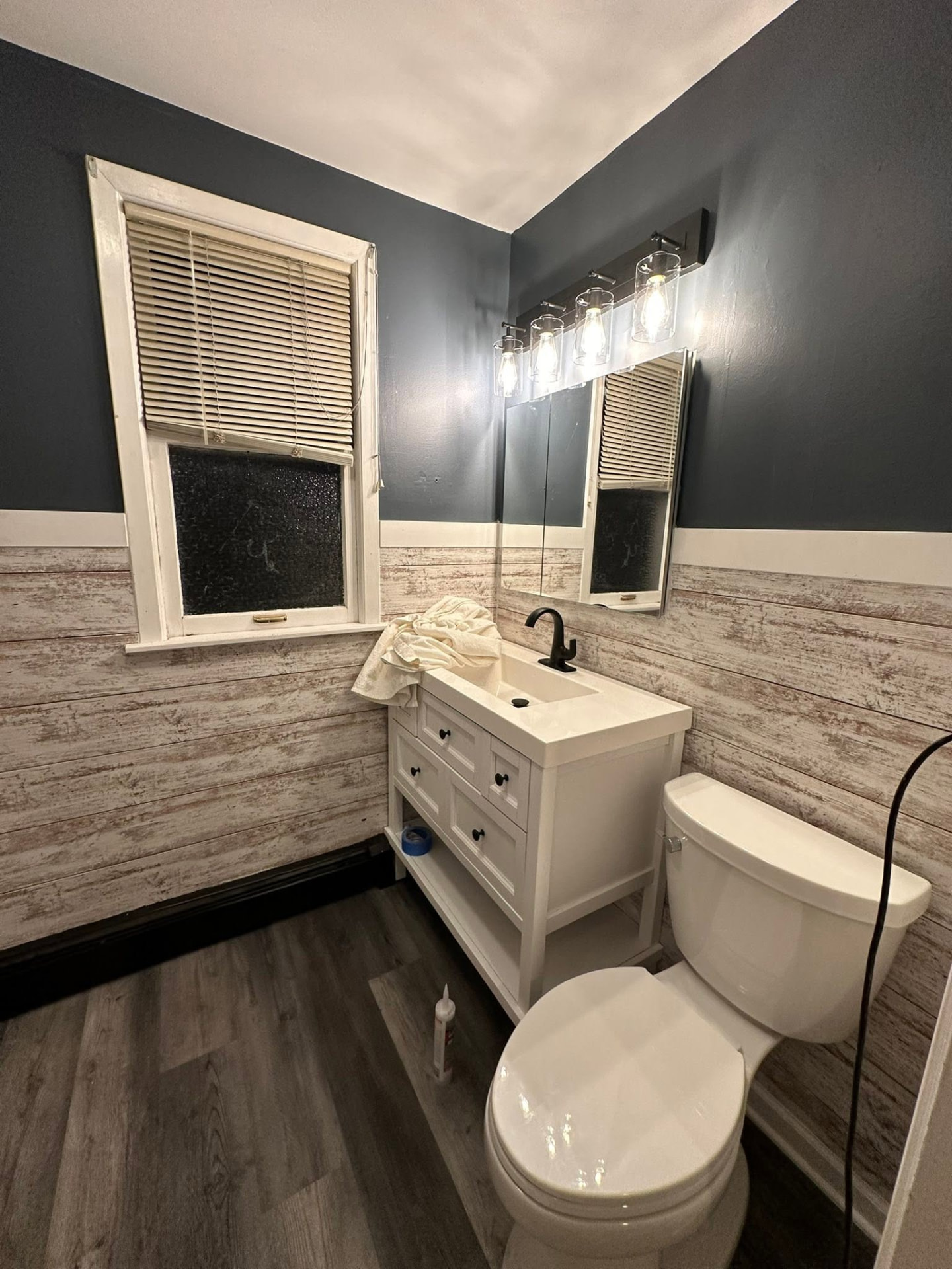 Remodeled bathroom with navy walls, shiplap wainscoting and new vanity