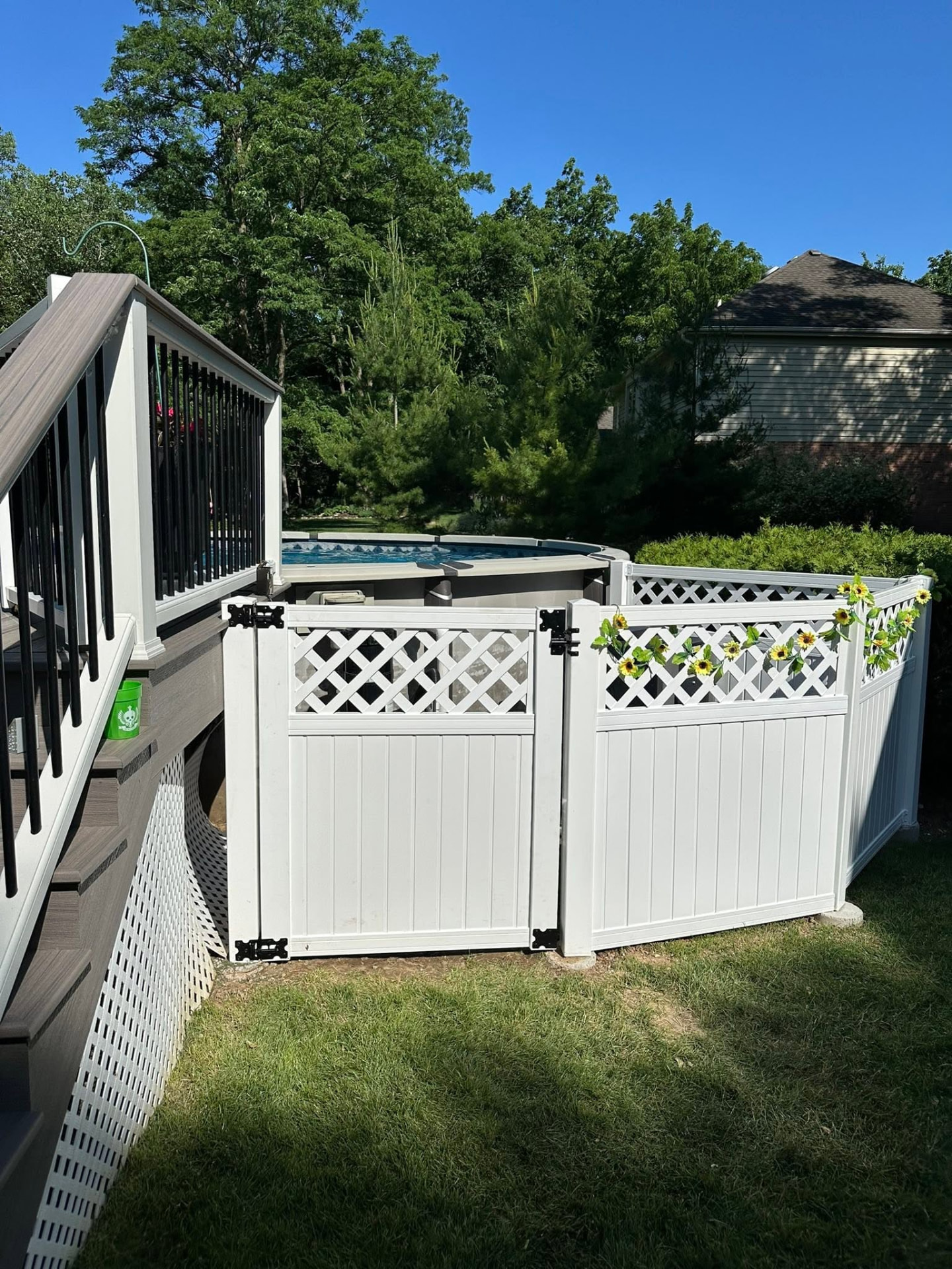 White vinyl privacy fence and gate enclosing an above-ground pool deck