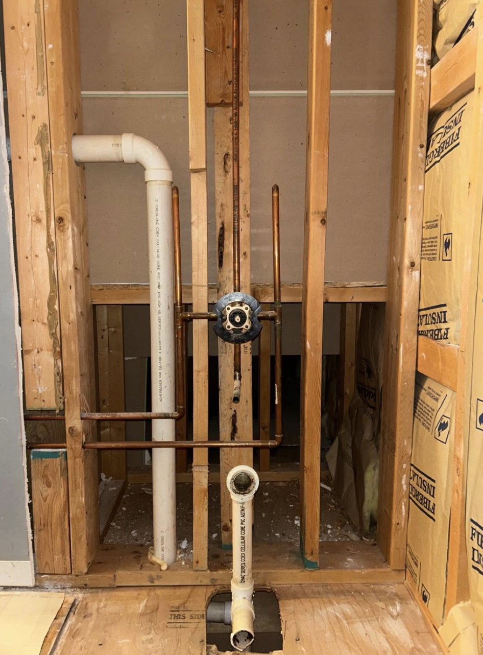 Bathroom plumbing wall opened for new shower and drain rough-in