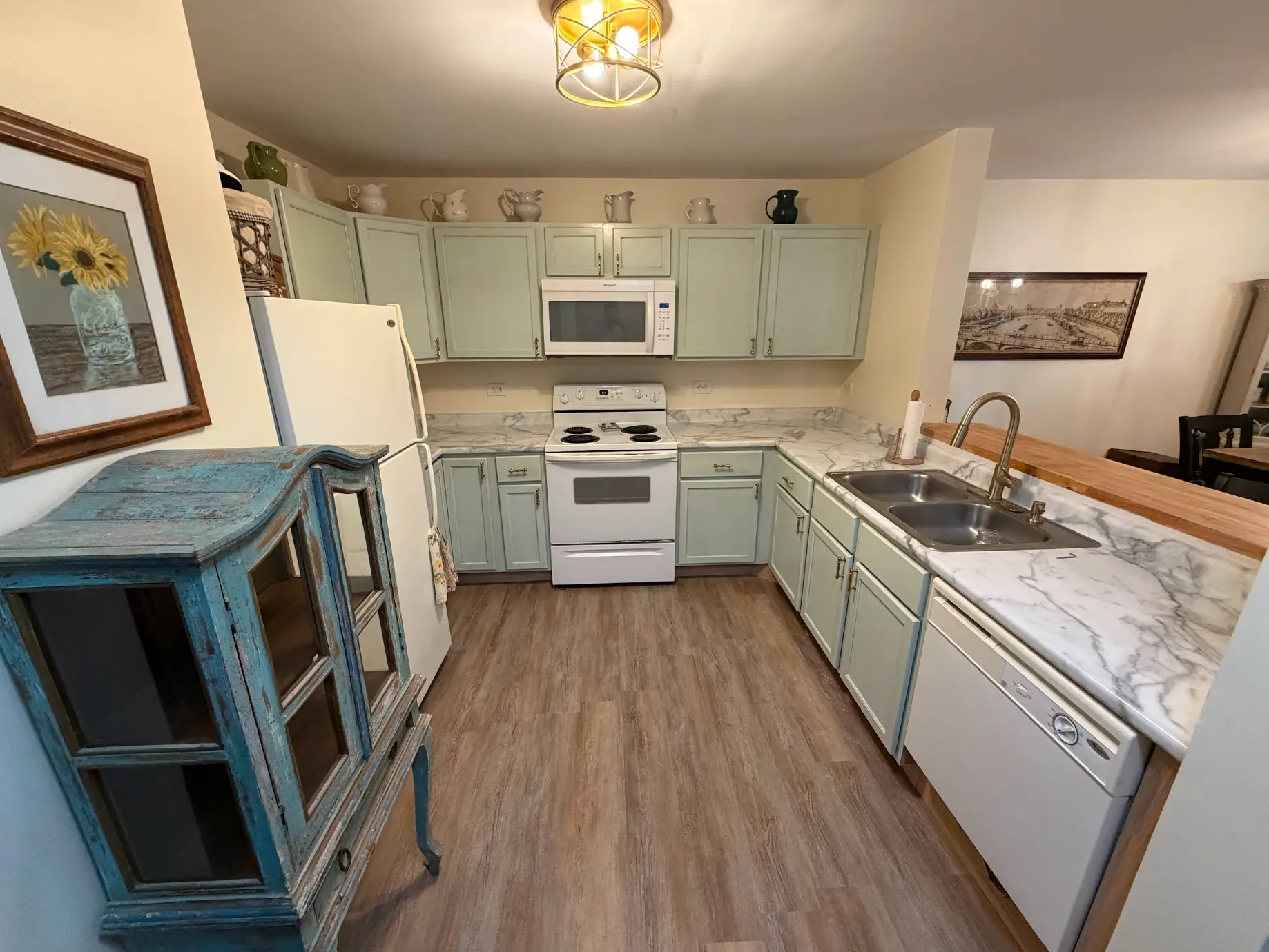Remodeled kitchen with soft green cabinets, marble countertops and stainless appliances
