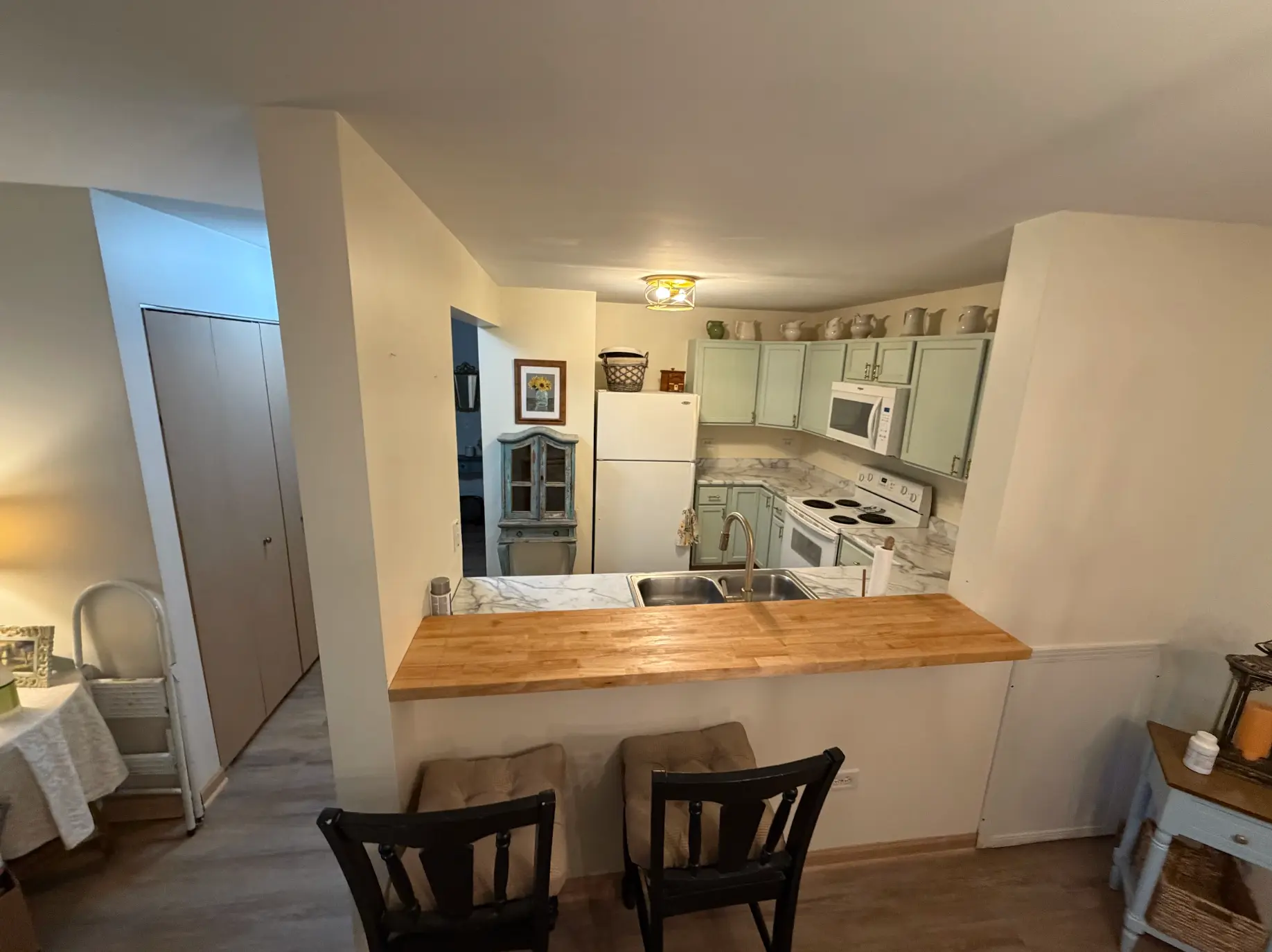 Remodeled kitchen with breakfast bar, green cabinets and wood countertop detail