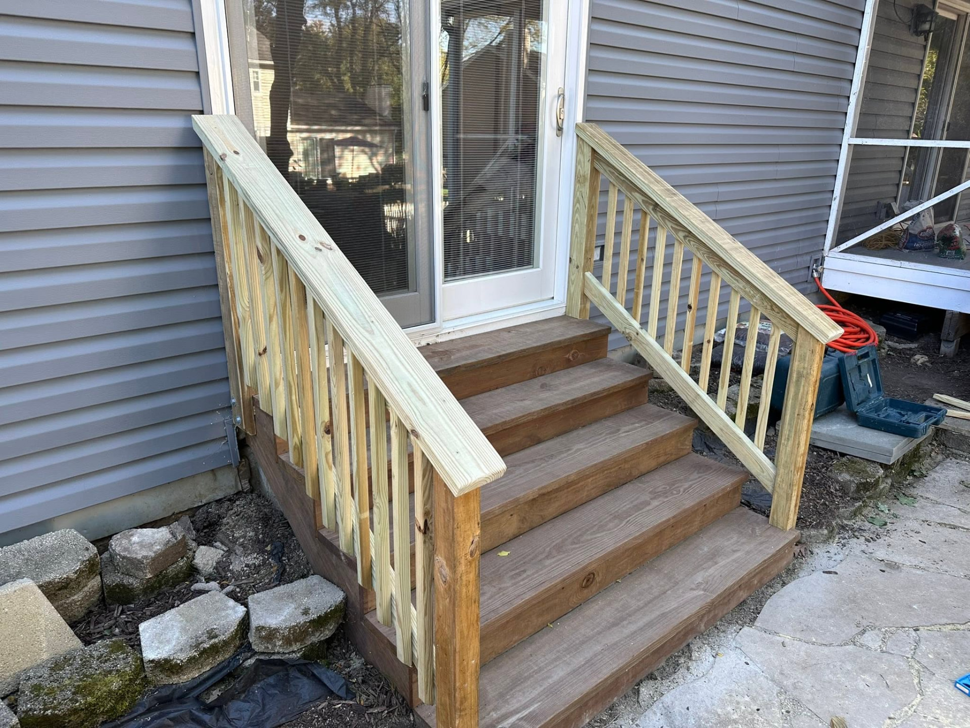 New pressure-treated stairs and railings at a sliding patio door