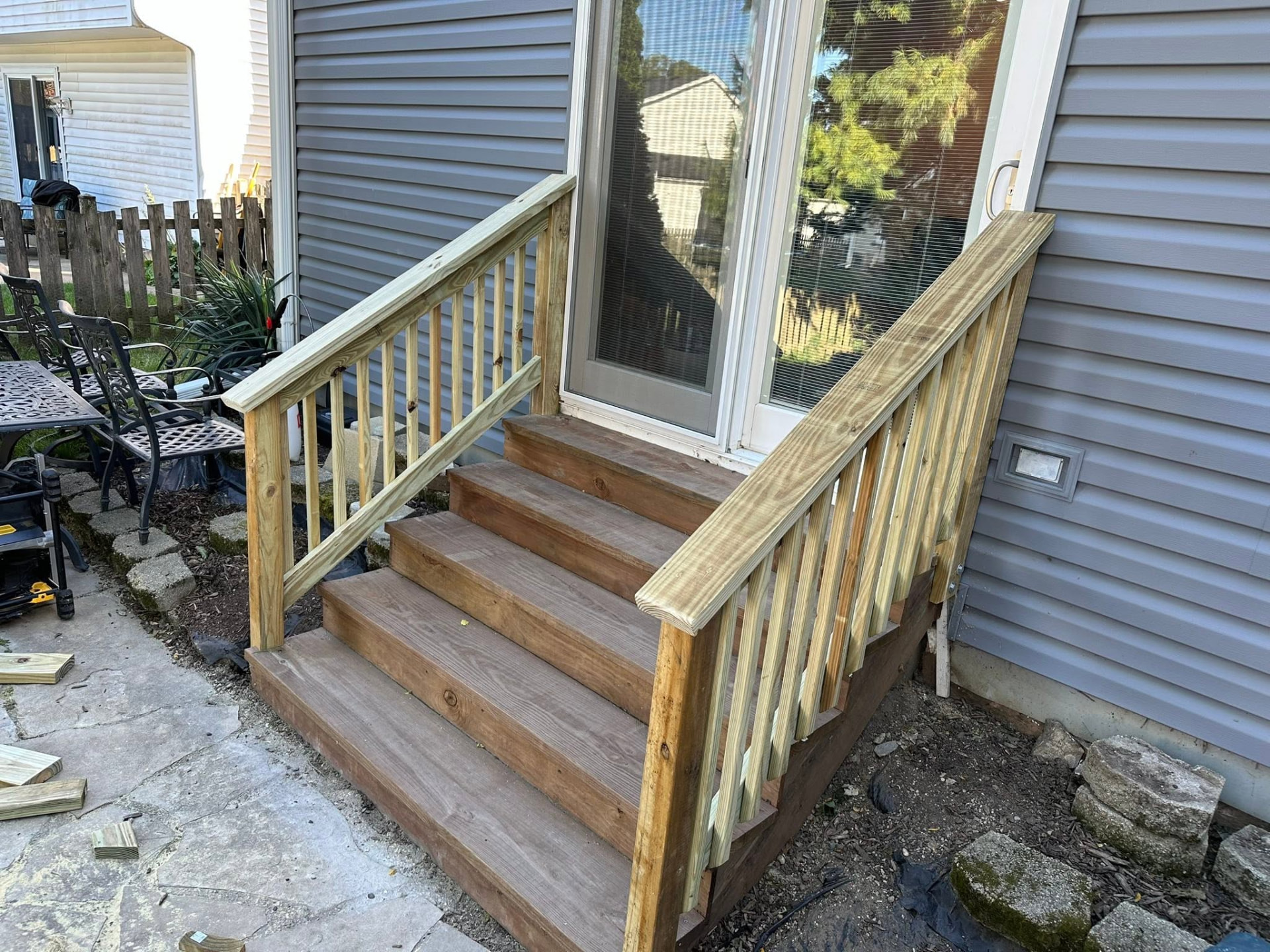 New pressure-treated deck stairs with handrails at a patio door