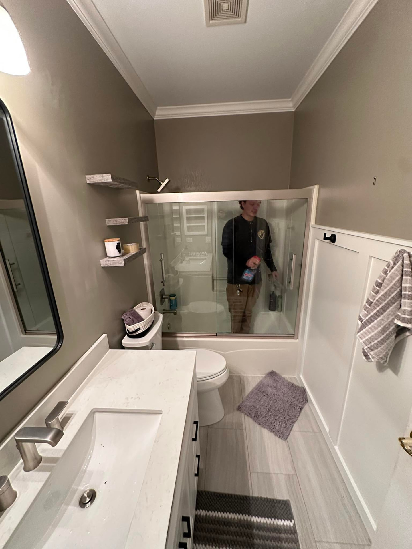 Finished bathroom with quartz vanity, tub-shower glass doors and board-and-batten trim