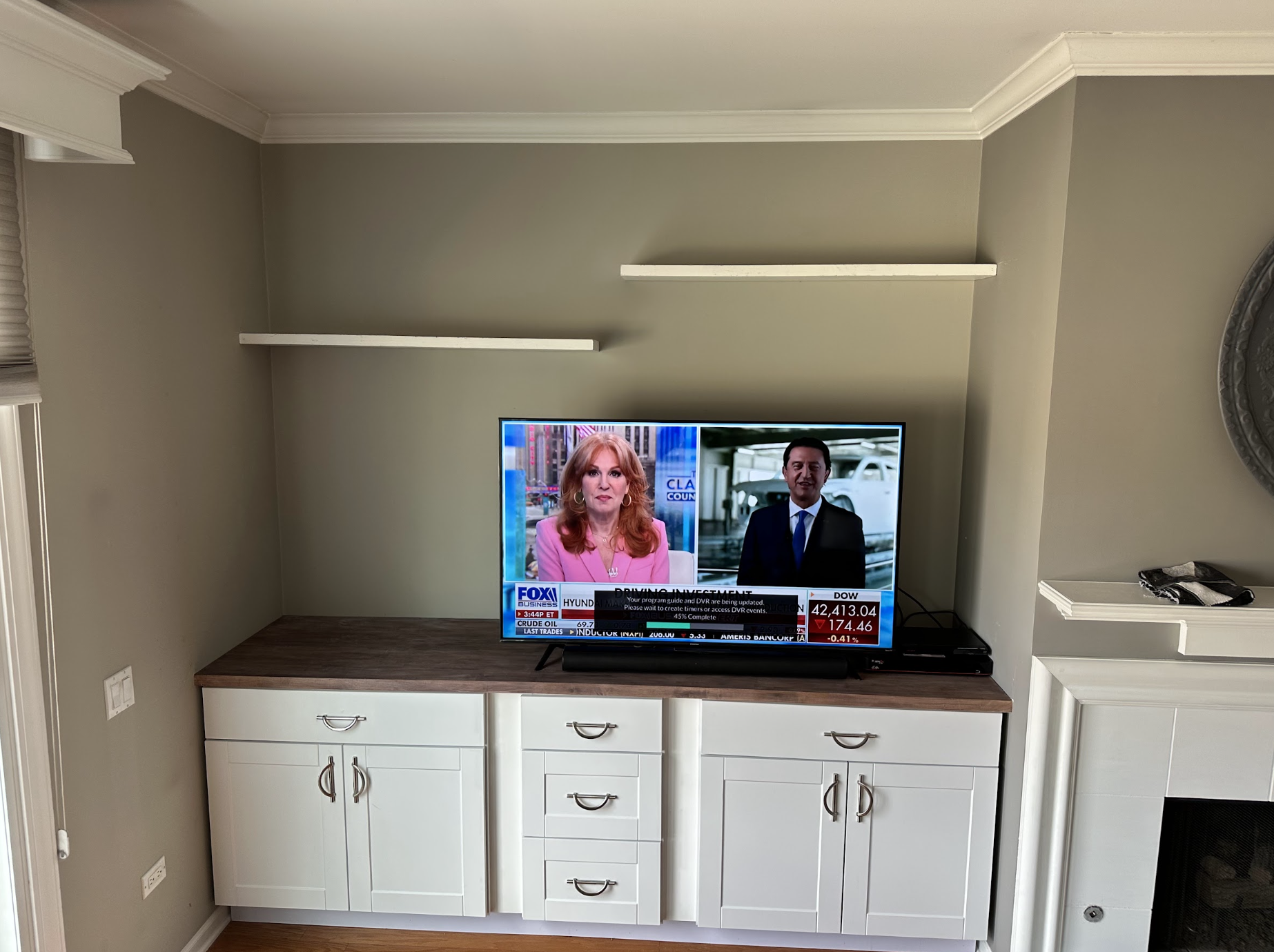Built-in media cabinet with white shaker doors, wood top and floating shelves