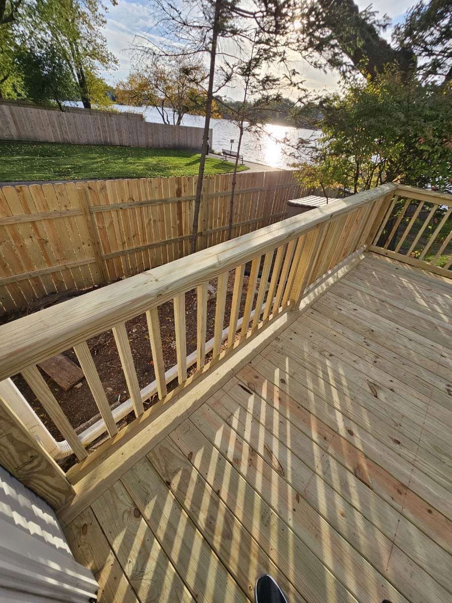 New pressure-treated deck and railing beside a new privacy fence
