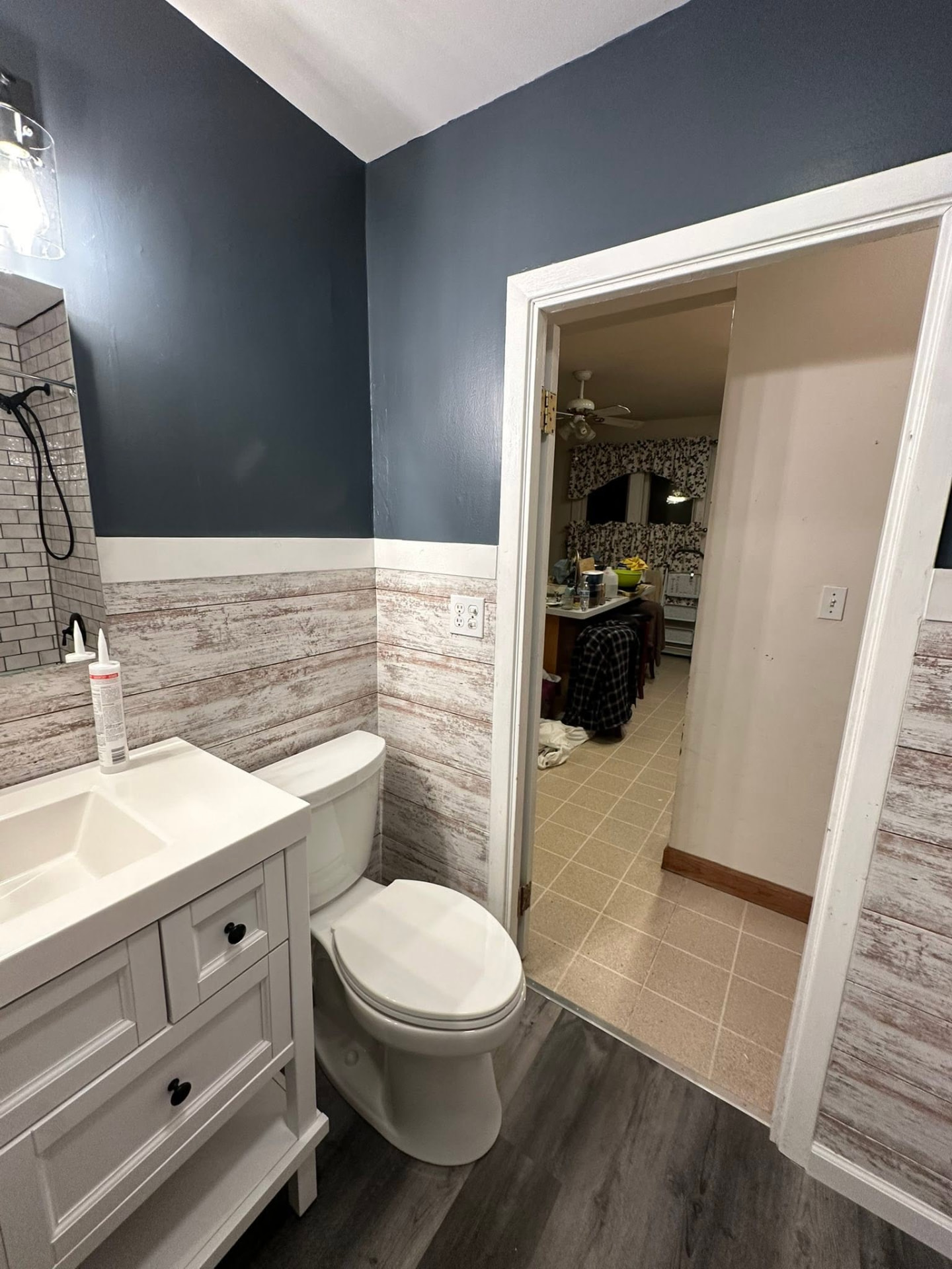 Remodeled half bath with navy walls, shiplap wainscoting and white vanity
